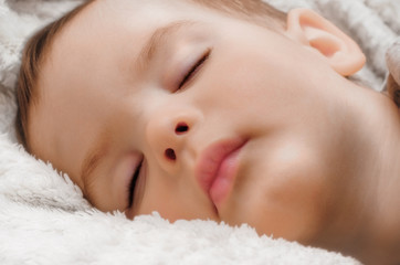 Portrait of asleep child on white fluffy plaid