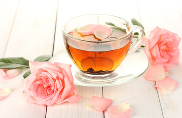 cup of tea with roses on white wooden table