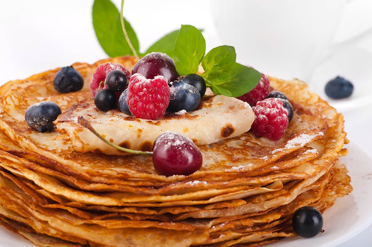 Pancakes with berries and mint on a white background