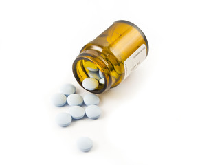 Pills pouring out of a bottle on a white background