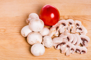 Mushrooms and tomato on wooden board