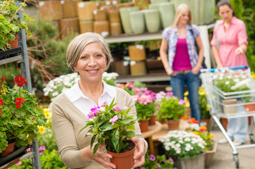 Garden centre senior lady hold potted flower