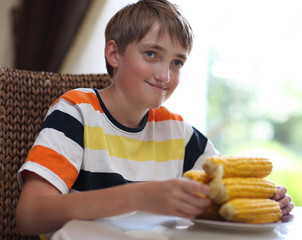 Portrait of a boy at the table with a plate of corn