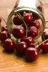 Cherry in glass jar isolated on the wooden background