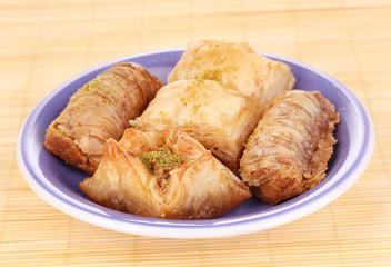 Sweet baklava on plate on bamboo mat