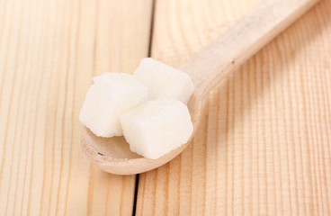 White sugar in spoon on wooden background