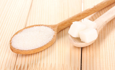 White sugar in spoons on wooden background