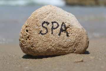 Fototapeta na wymiar Słowo SPA napisane na skale, na plaży