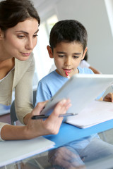 Teacher and schoolboy using electronic tablet in class