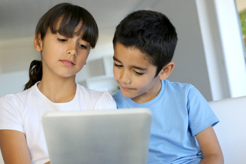 Children playing with electronic tablet at home