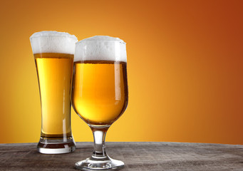 Beer into glass on golden background