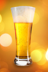Beer into glass on golden background