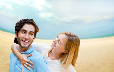 Portrait of young couple in love embracing at beach and enjoying