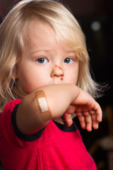 Injured boy with cut nose and adhesive bandage on elbow