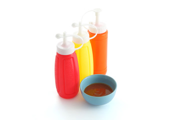Red chili sauce and three color bottle on white desk.