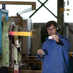 Blue collar worker at machine in factory