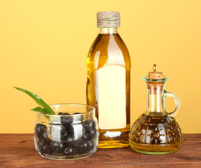 Olive oil bottle and small decanter on yellow background