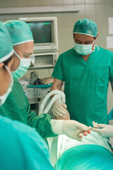 Medical team taking a scalpel from the hand of a colleague