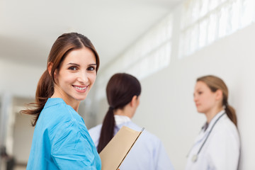 Smiling nurse  while standing in a hallway with a patient and a