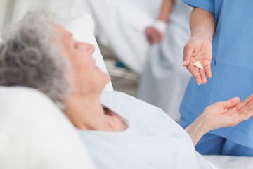 Obraz na płótnie Canvas Nurse giving drugs to an elderly patient