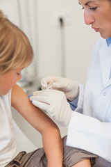 Obraz na płótnie Canvas Doctor injecting liquid in a child arm