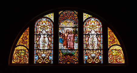 Stained glass window depicts the baptism of Jesus.