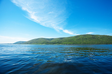 mountain with trees against the blue sky and the river