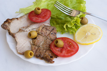 Appetizing fried meat with vegetables and olives