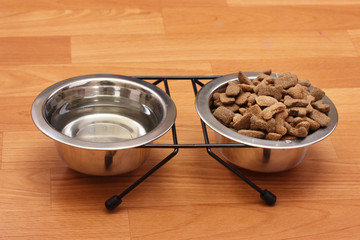 dry dog food and water in metal bowls on the floor