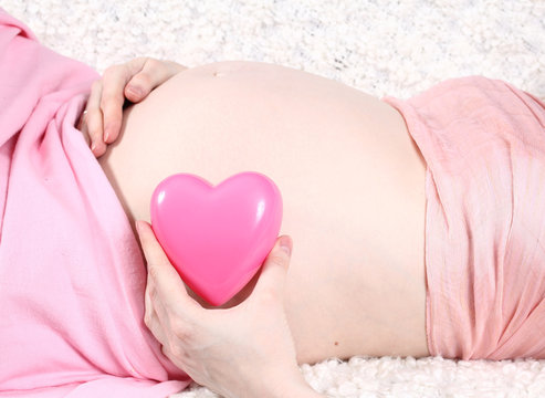 stomach of the pregnant girl and pink heart