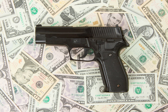 Black gun isolated on a heap of money