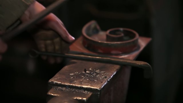 smith working with hot metal on anvil