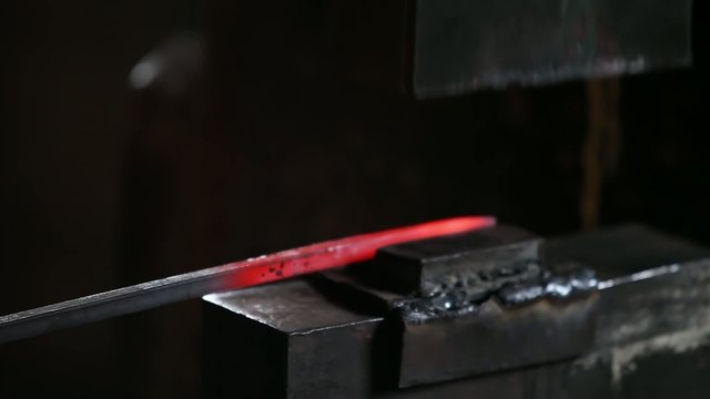 smith working with hot metal on anvil