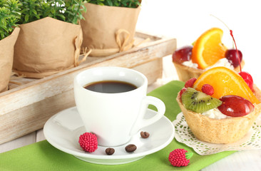 cup of coffee and sweet cakes with fruits on wooden table