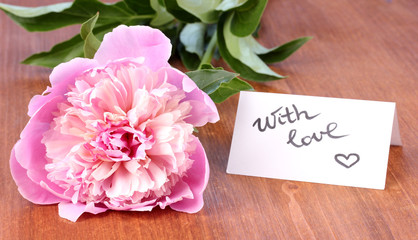 Pink peony with card on wooden background