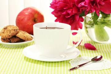 cup hot chocolate, apple, cookies and flowers on table in cafe