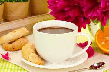 cup hot chocolate, cookies and flowers on table in cafe