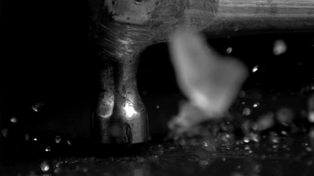 Hammer in super slow motion befalling on an ice cube