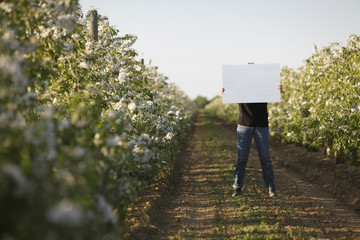 Caucasian woman holding blank placard in crop row