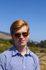 cool teenage boy with sunglasses walks happy on the meadow