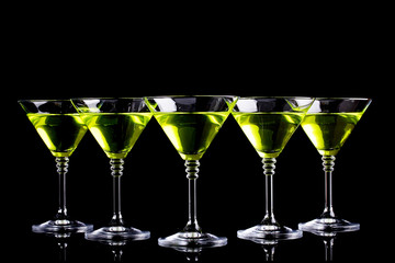 Yellow cocktail in martini glasses isolated on black
