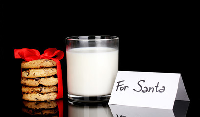 Glass of milk and cookies isolated on black