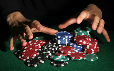 Fototapeta na wymiar ¯etony do pokera i ręce nad nim na zielonym stole