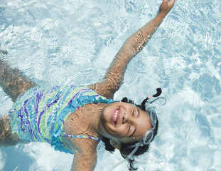 Hispanic girl floating in swimming pool