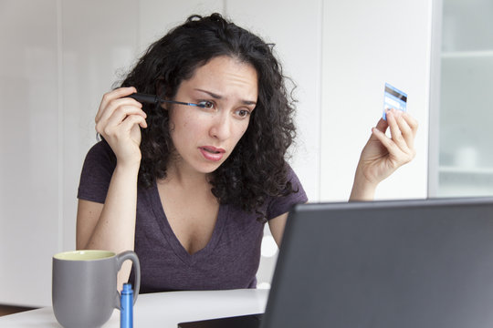 Hispanic woman putting on make up, drinking coffee and using laptop
