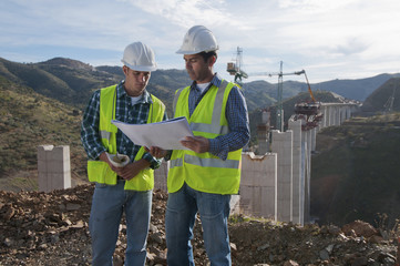 Construction workers looking at blueprint at construction site
