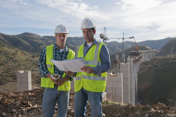 Construction workers looking at blueprint at construction site