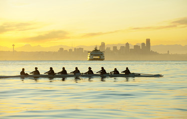 Team rowing boat in bay