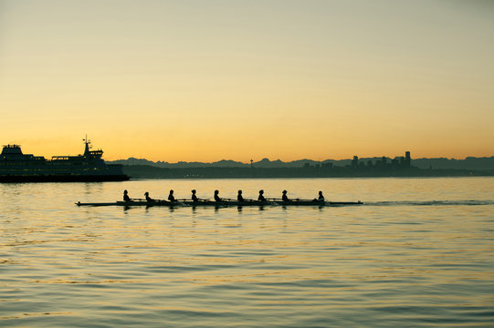 Team rowing boat in bay
