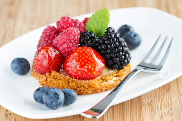fruit cake with berries  on white plate with a fork